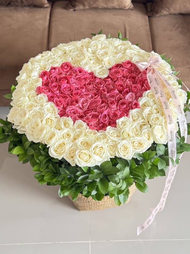 A luxurious heart-shaped basket arrangement of 171 white and candy Holland roses