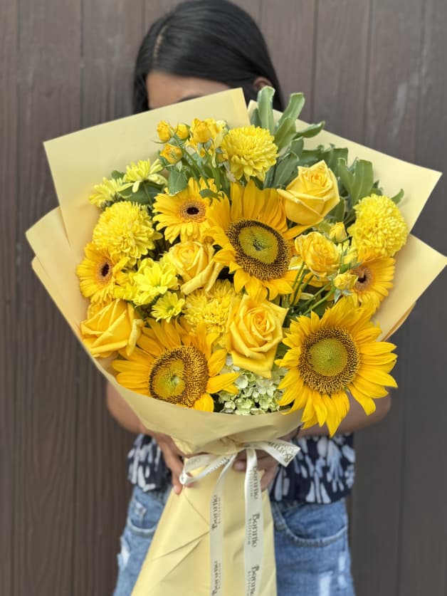 A cheerful bouquet of yellow sunflowers, roses, and chrysanthemums
